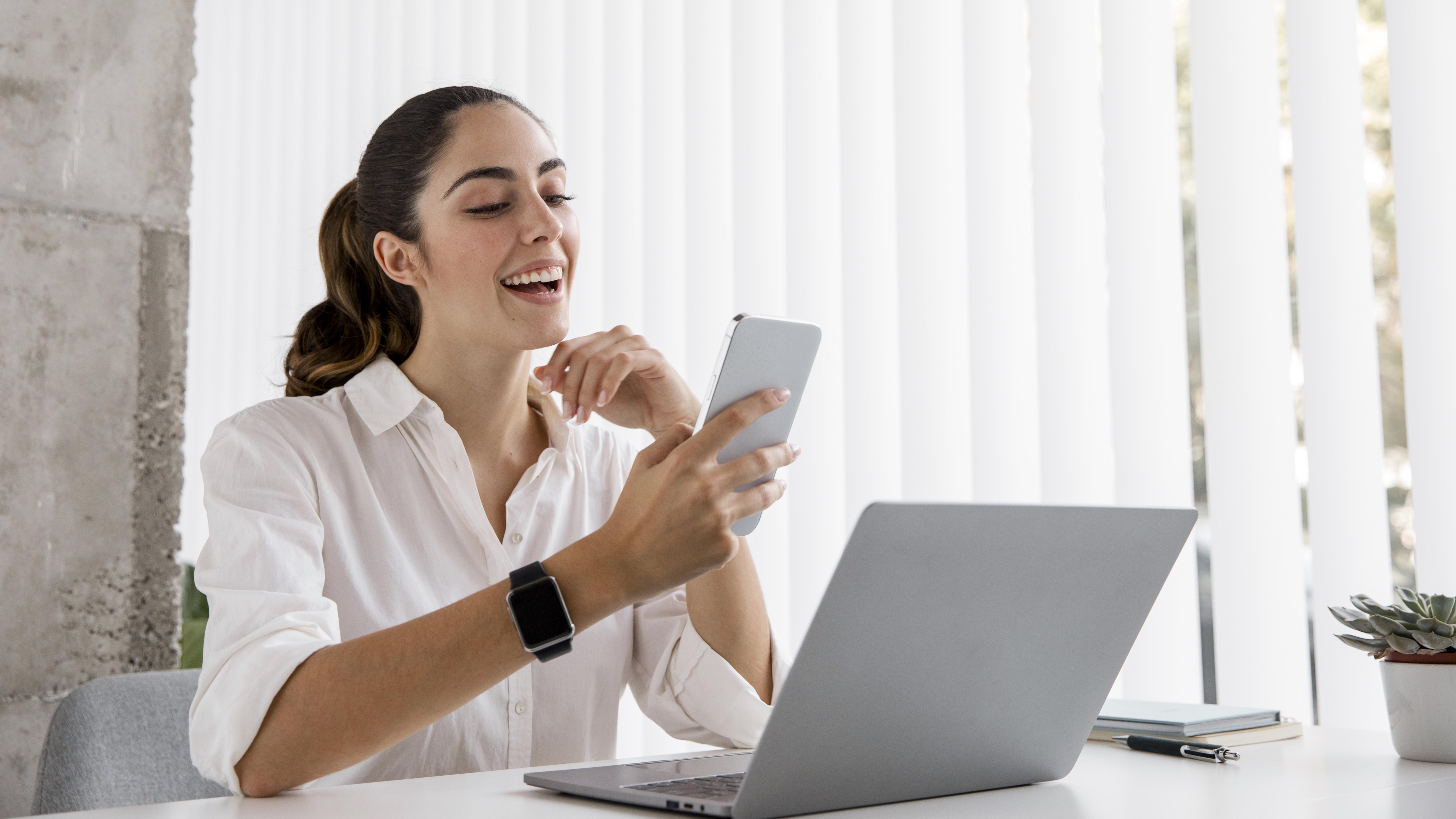 Médica en espacio de trabajo clínico con teléfono y computadora portátil